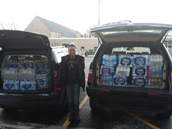 Fairfax Fifth Grader James Greene stands near the donations after he launched a bottled water collection for residents of Flint, Michigan.