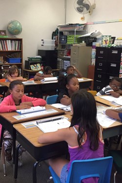 Students meditating with eyes closed at desks