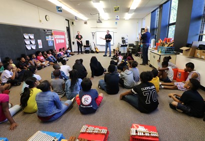 Students sitting on floor listening to adult speakers