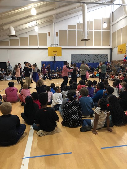 Fifth graders dancing on gym floor with crowd sitting around them