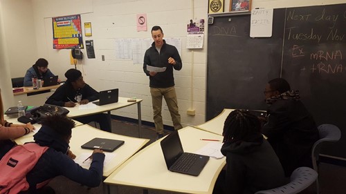 Young man standing in front of group of students in classroom