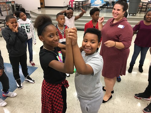 Two students dancing with other students and teacher watching