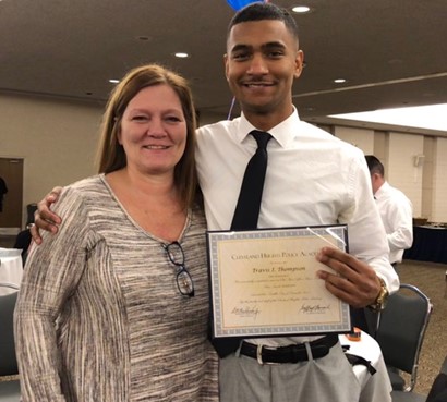 Travis with woman and holding diploma