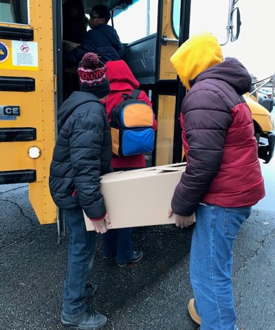 Two students loading box onto bus