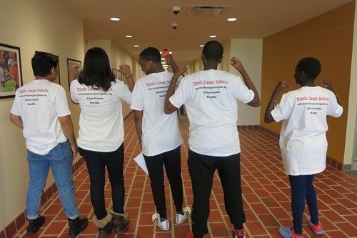 Group of students pointing to back of shirts