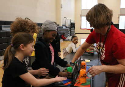 students and teacher playing cup stacking game