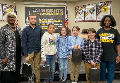 five students standing with board president and superintendent