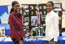 two girls in front of poster and trophy