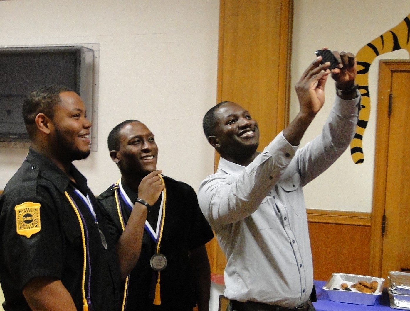 Counselor David Peake takes a selfie with two graduates.