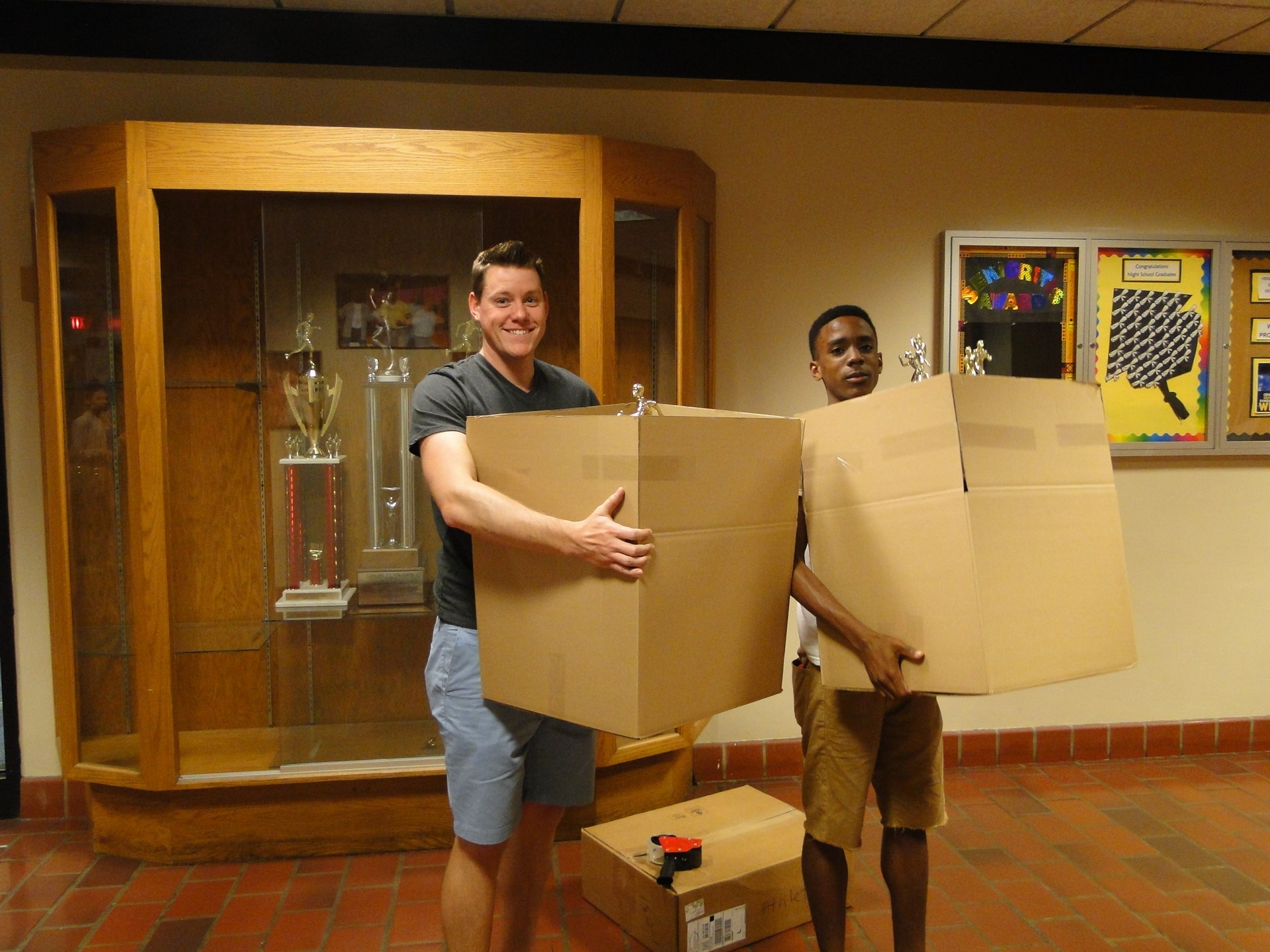 Athletic Department Assistant Peter Eckendorf (L) and student volunteer empty trophy cases.