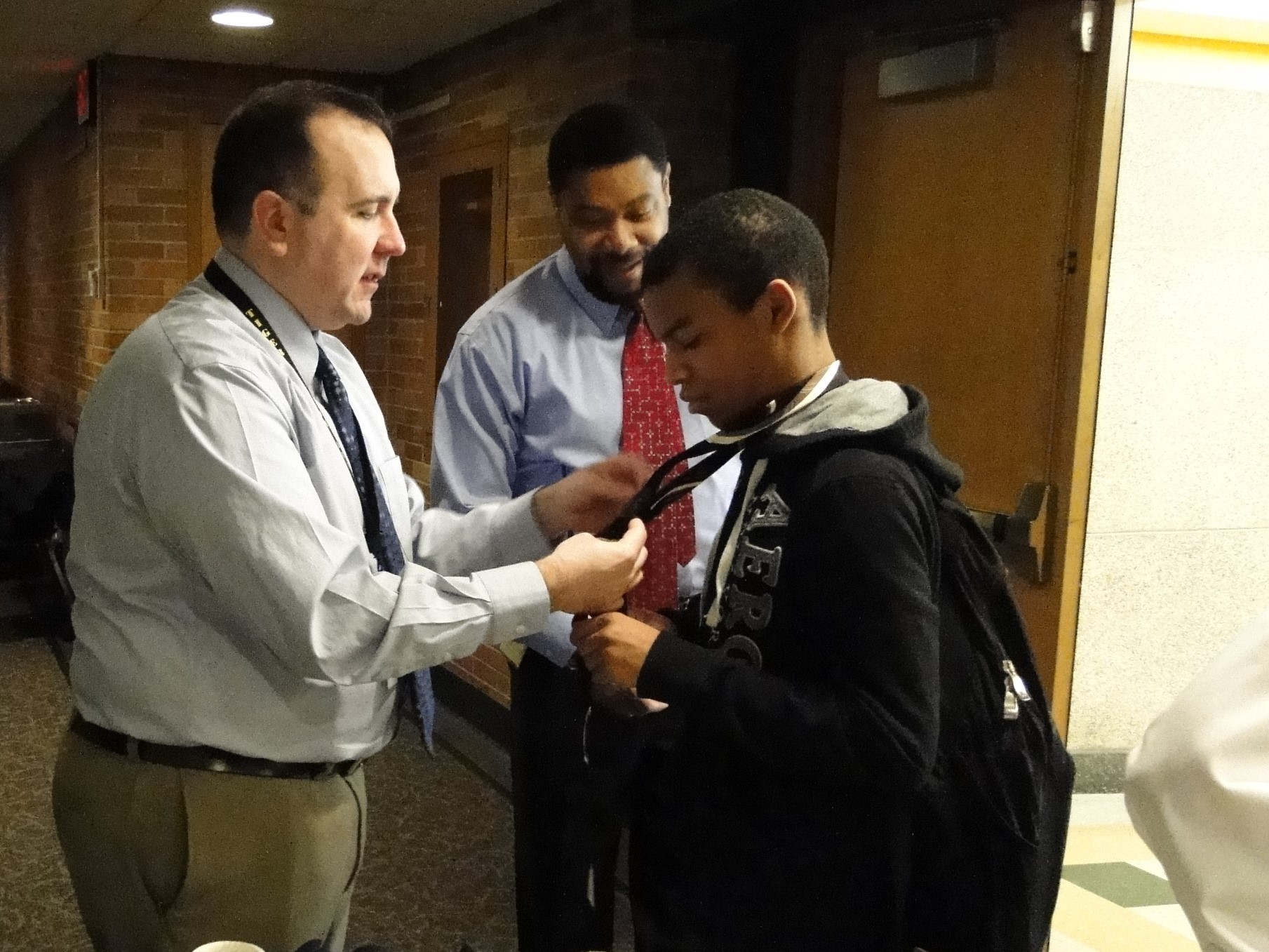 Administrator Bob Swaggard helps a student with his tie.