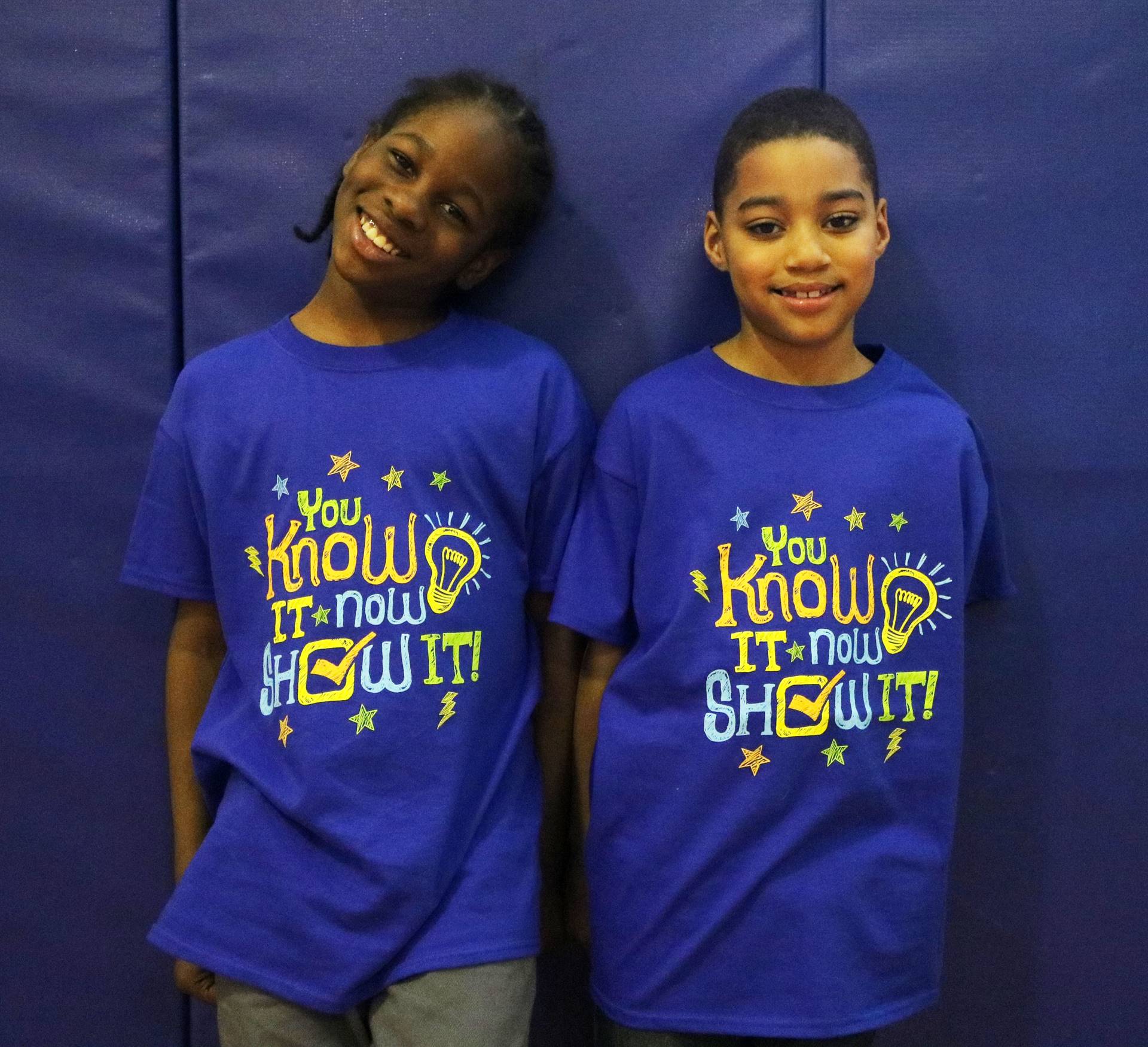 Two students with blue shirts that say You Know It Now Show It