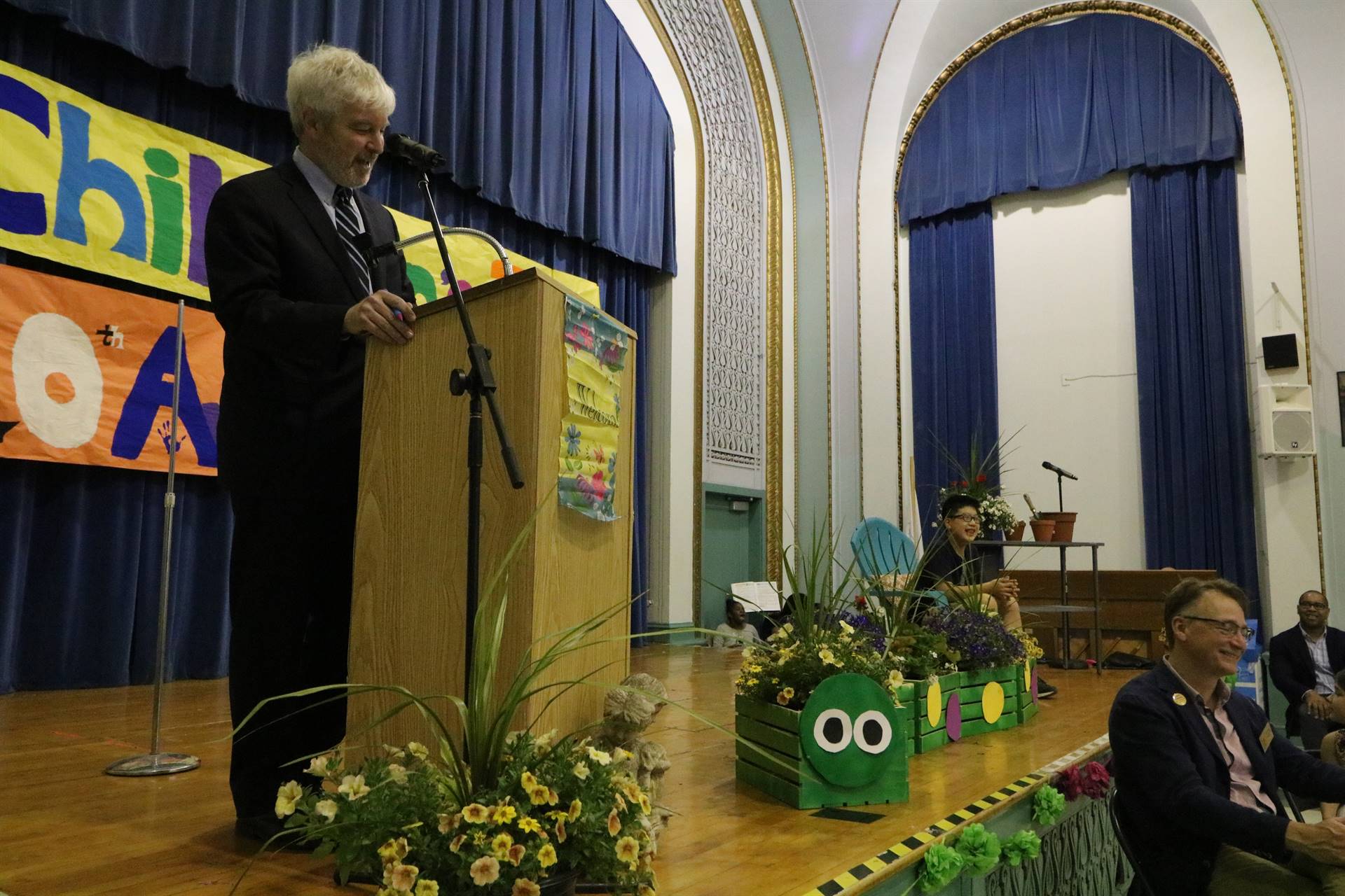 Male reader at podium with student sitting