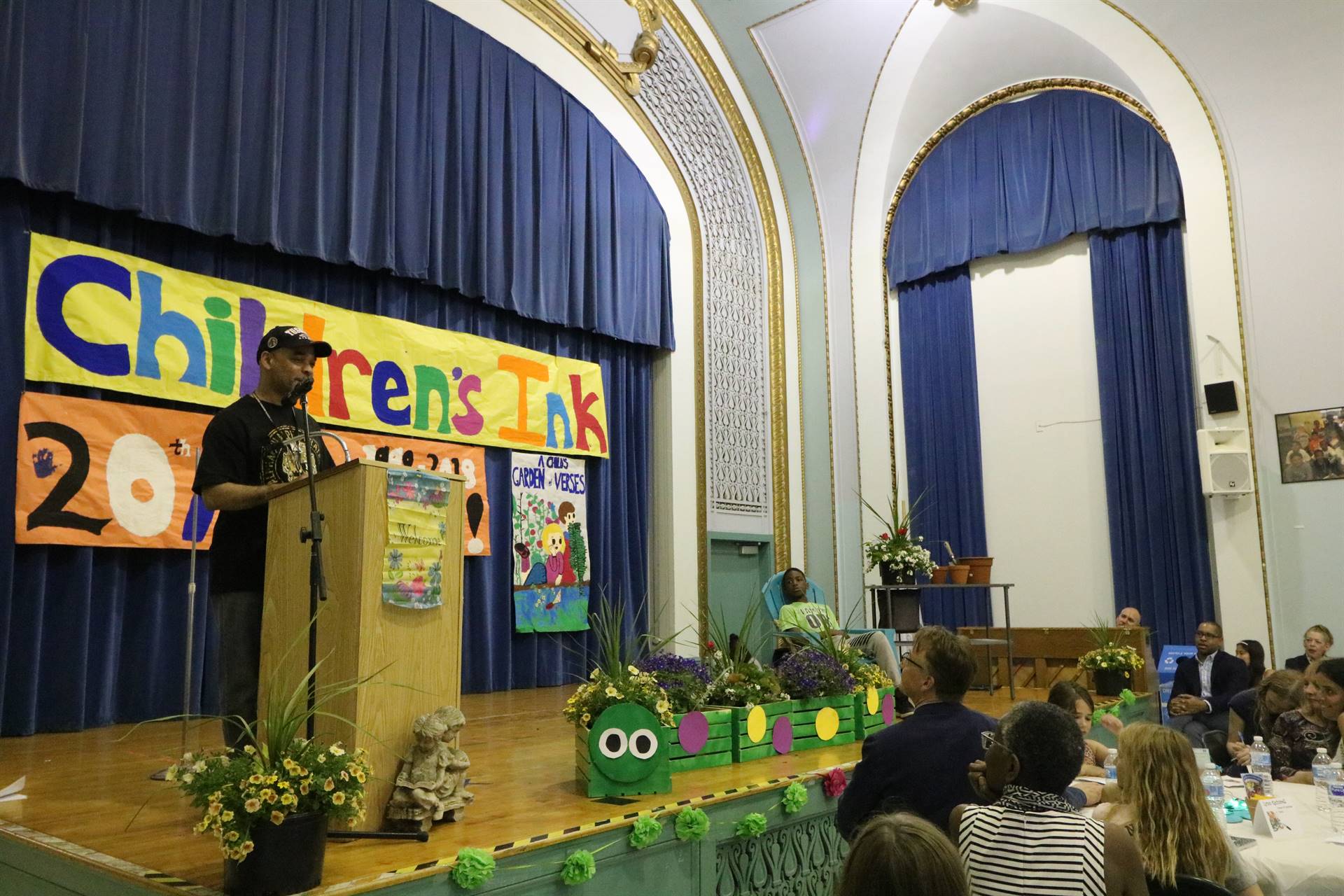 Male reader at podium with student sitting