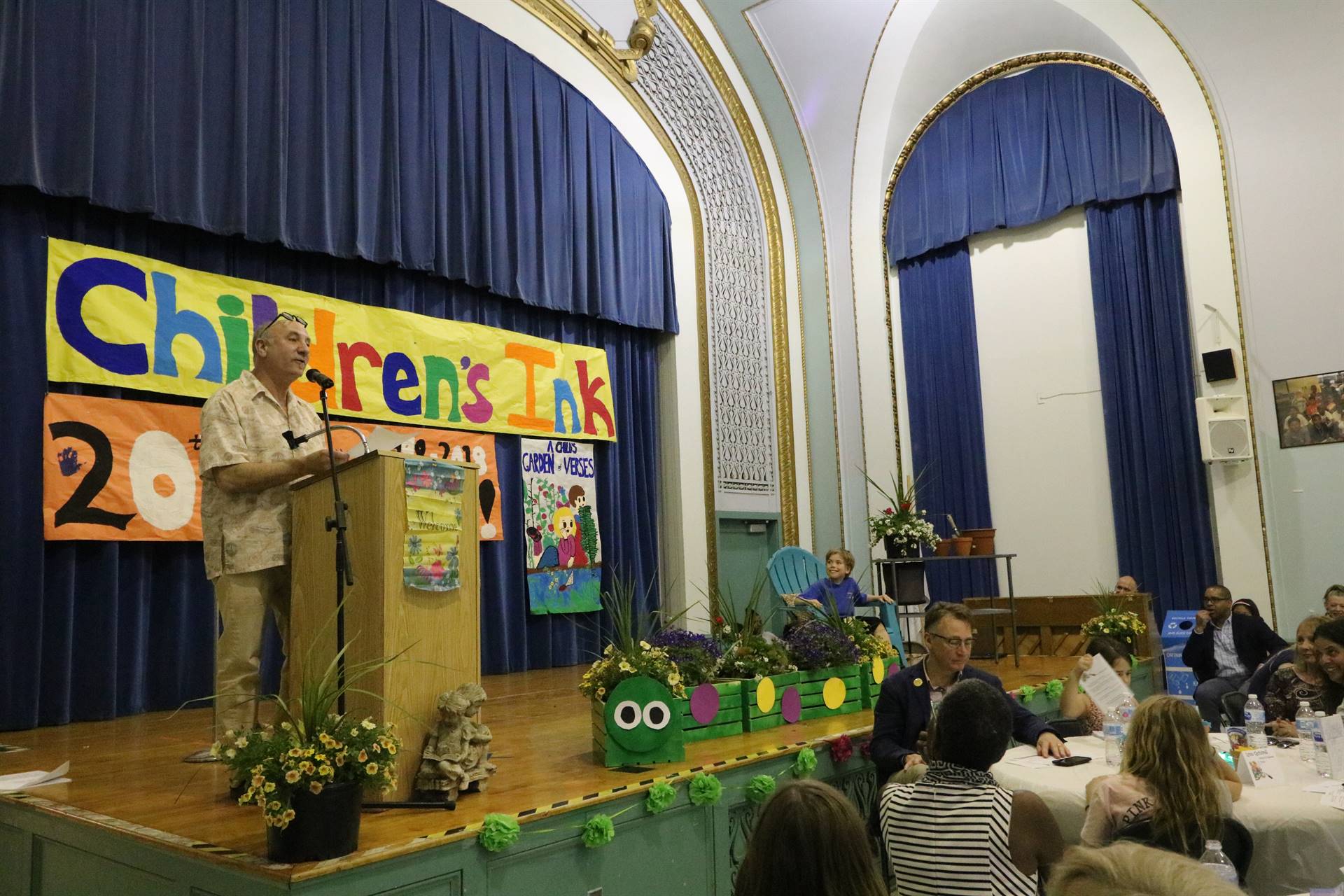 Male reader at podium with student sitting