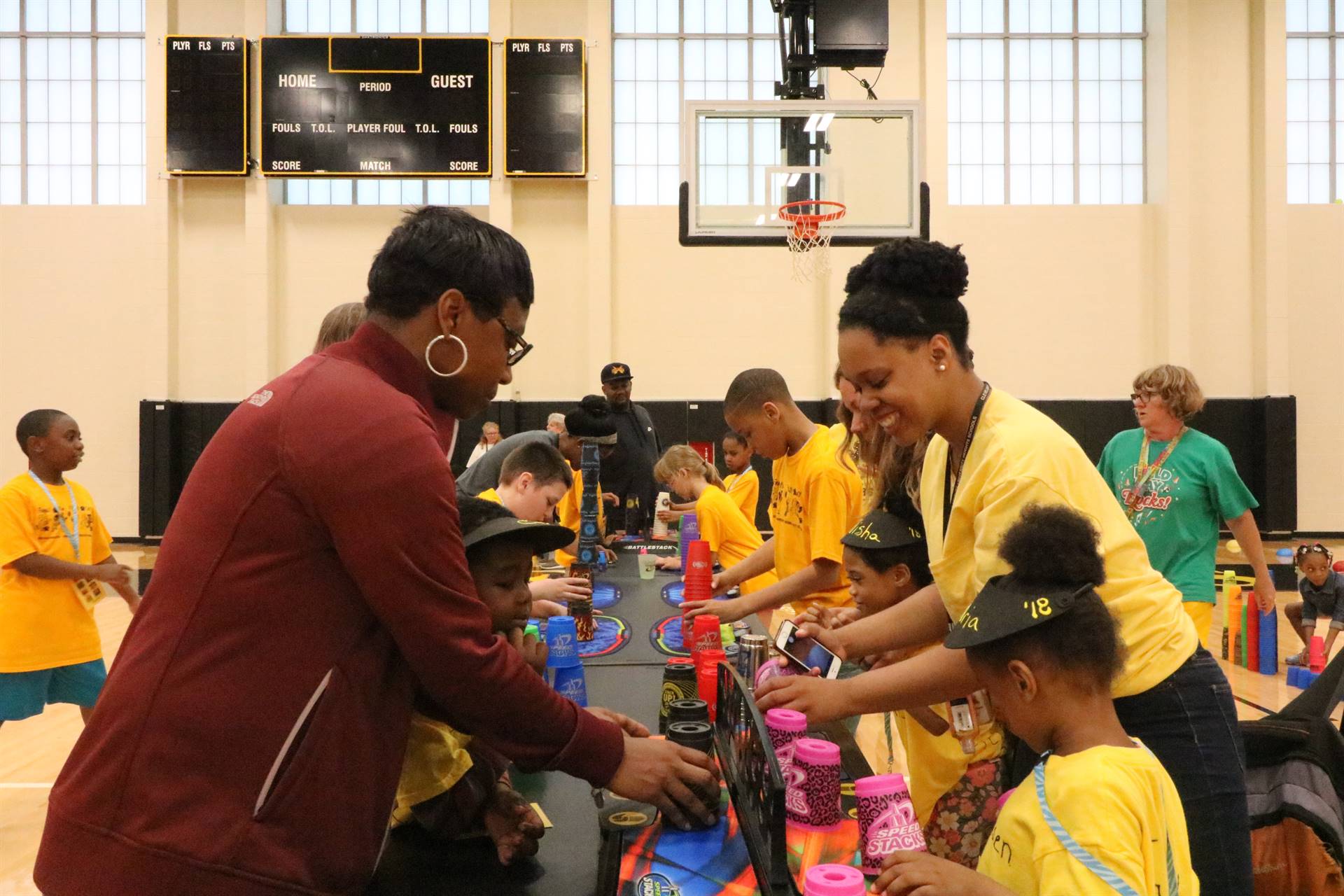 Kids and adults playing cup stacking game at table