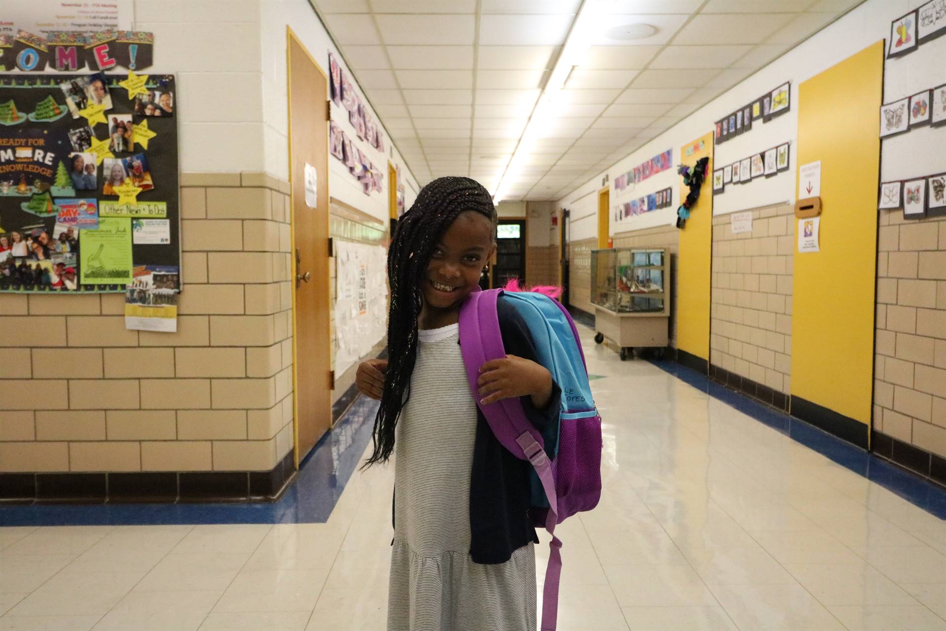 Young girl smiling with bookbag