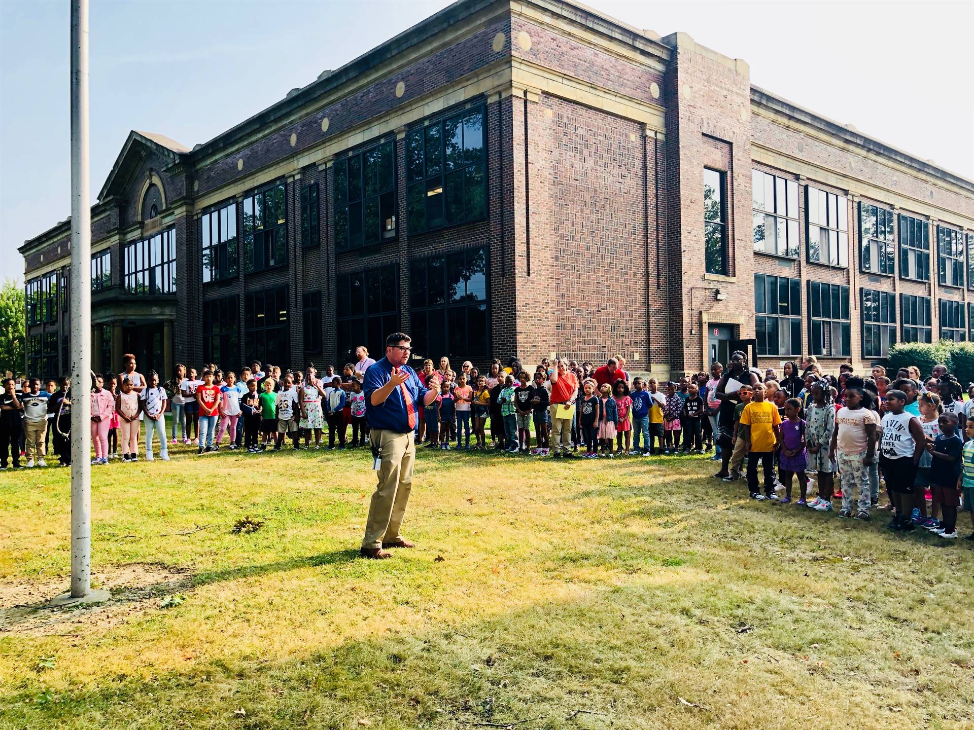 Principal talking to group by flagpole