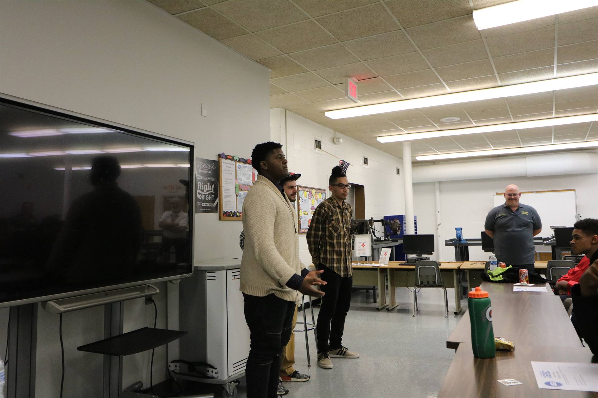 three students speaking to class